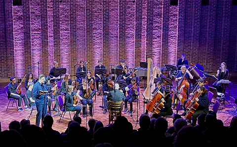 Wide shot of orchestra and narrator